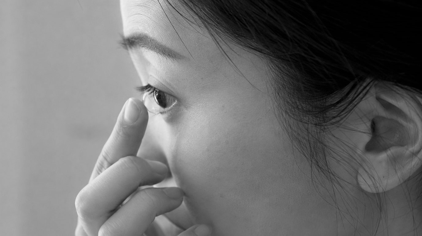 Close-up seseorang melepas softlens dari mata, dilihat dari samping