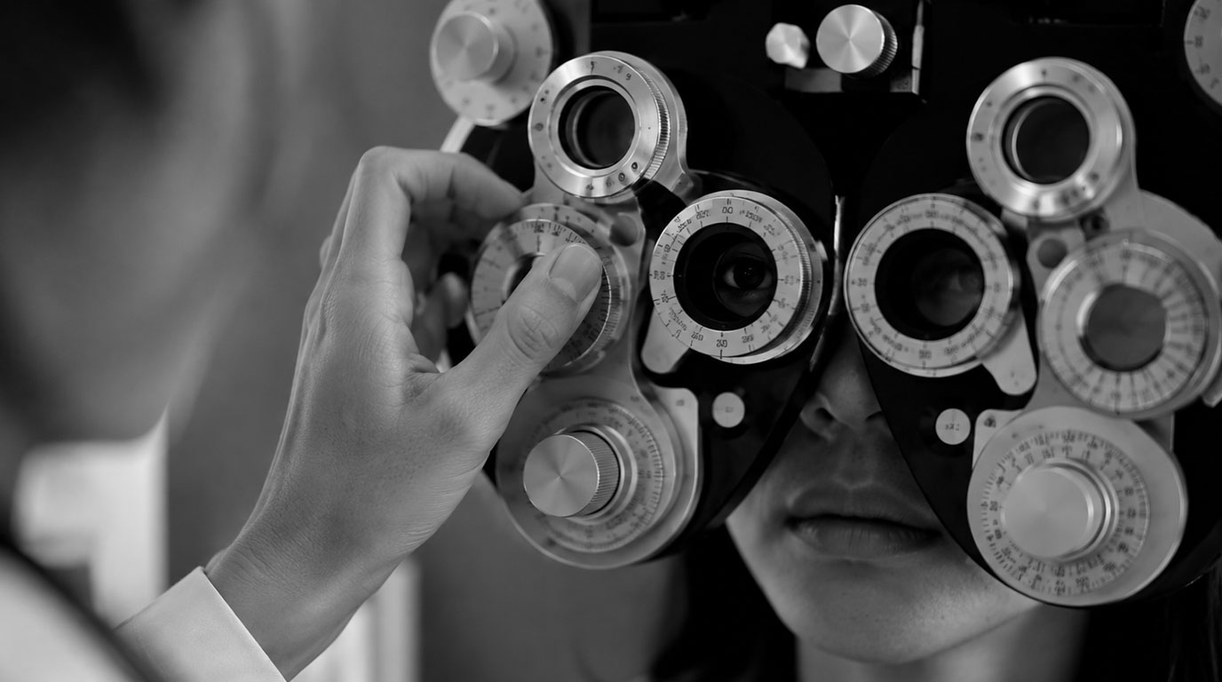 Optisien melakukan pemeriksaan refraksi mata dengan alat phoropter di toko optik
