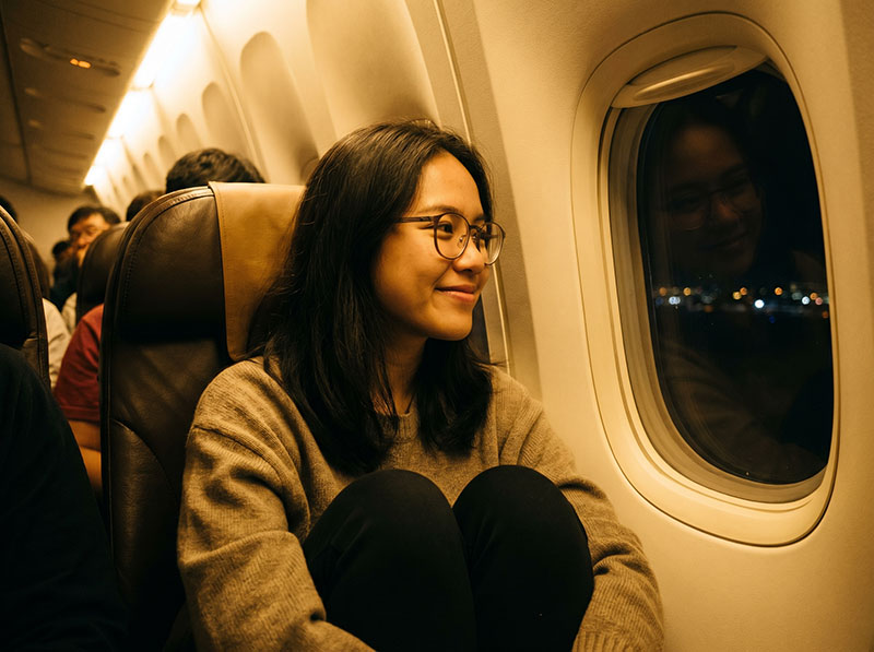 Woman at airplane window with glasses